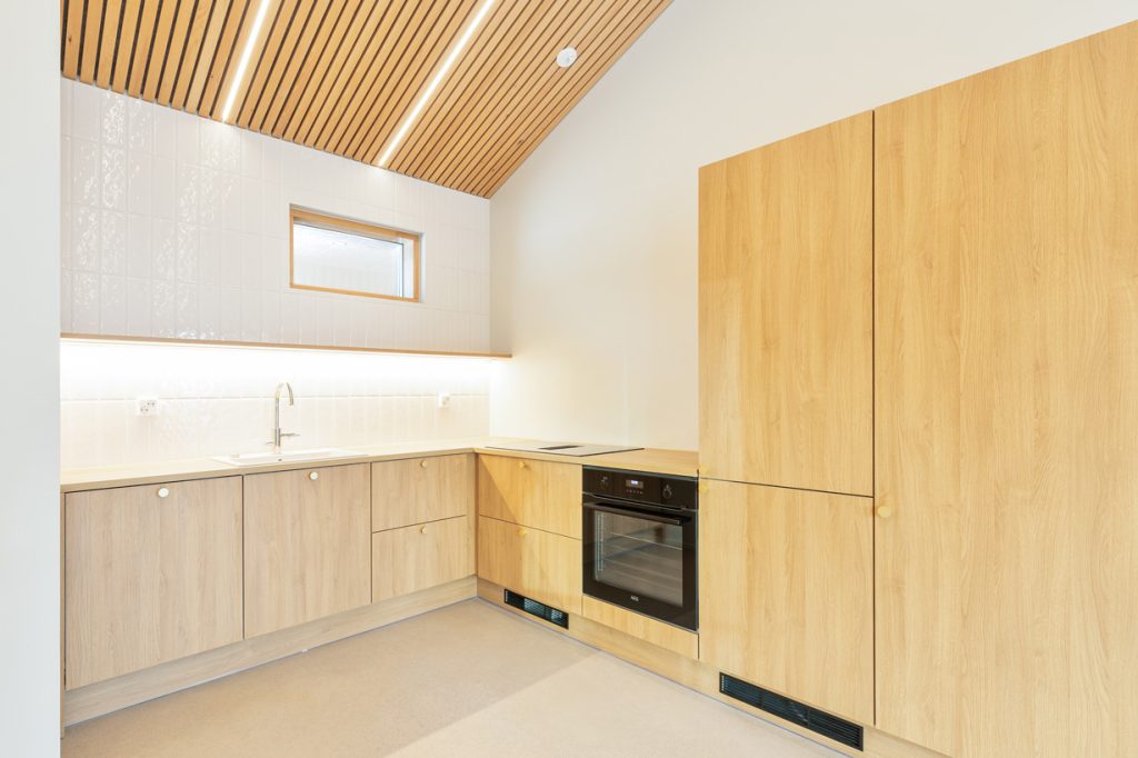 Espoon uudiskohteen moderni keittiö, puunsävyiset kaapistot ja vaalea sisustus.