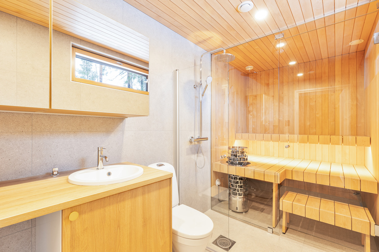 Espoon uudiskohteen kylpyhuone ja sauna, moderni lasiseinä ja puupanelointi.