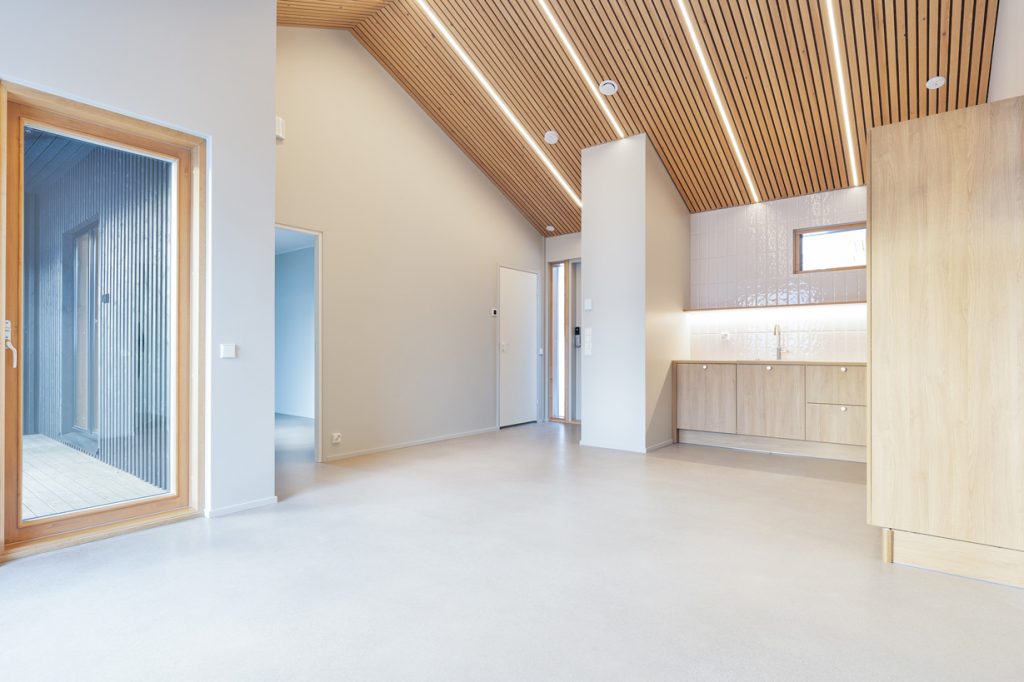 Uudiskohteen paritalon valoisa olohuone ja keittiö Espoossa, korkea puupaneelikatto ja moderni sisustus.