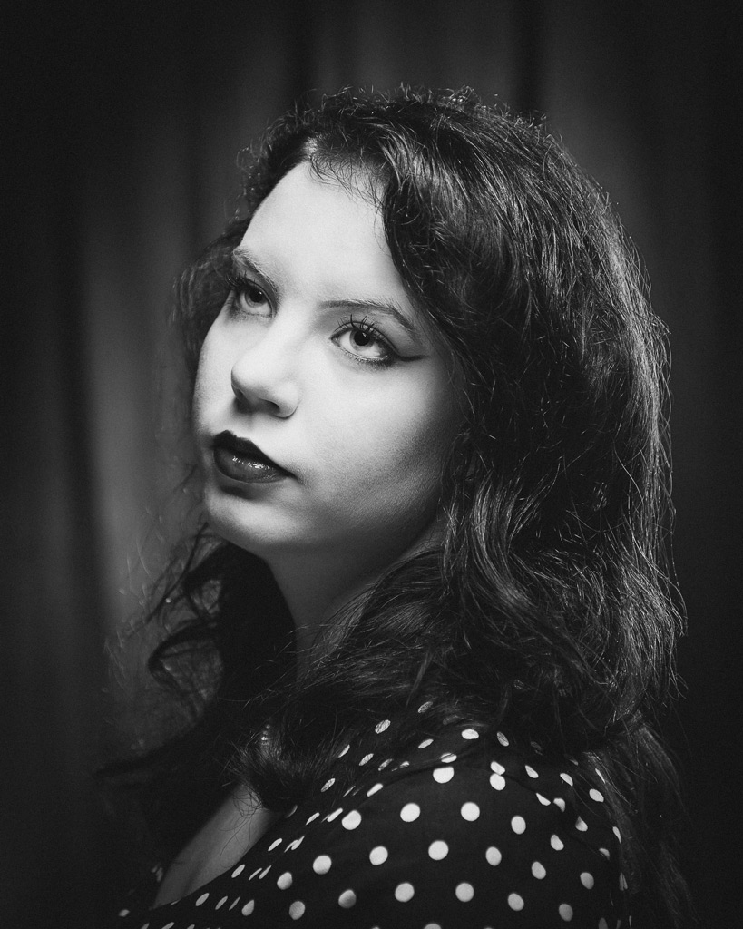 Mustavalkoinen muotokuva, henkilö katsoo ylöspäin retrohenkisessä Old Hollywood -tyylissä.